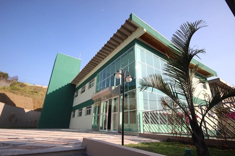 Fachada de um edifício moderno com fachada de vidro e detalhes em verde.